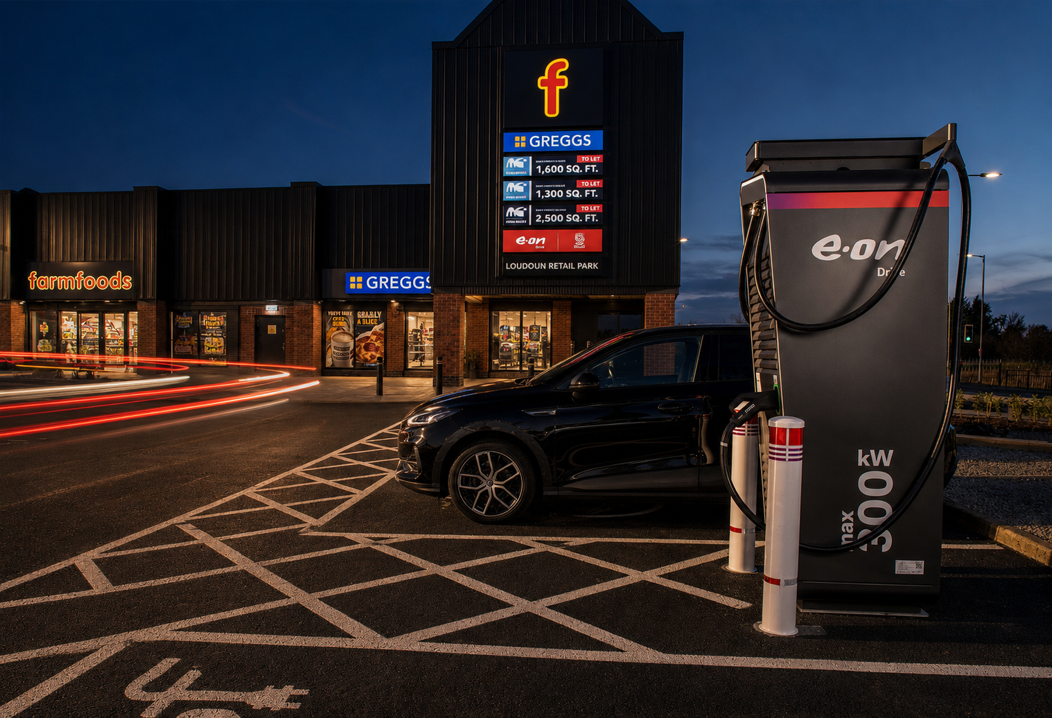 E.ON Drive ultra-rapid charging bay at Loudoun Retail Park at dusk, with Farmfoods and Greggs in the background
